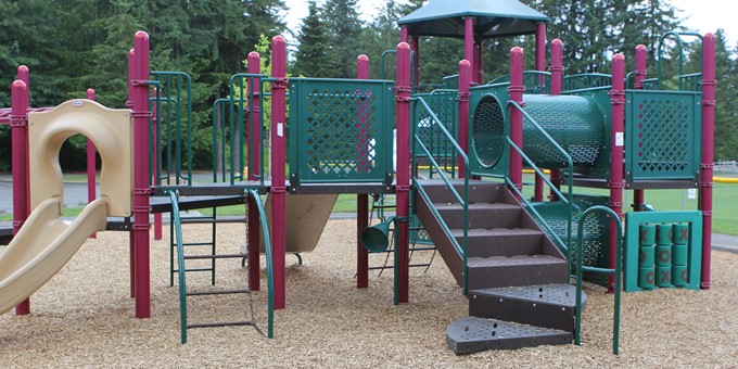 Outdoor playground unit containing slides, steps, crawling tunnels, and a tic-tac-toe game board.