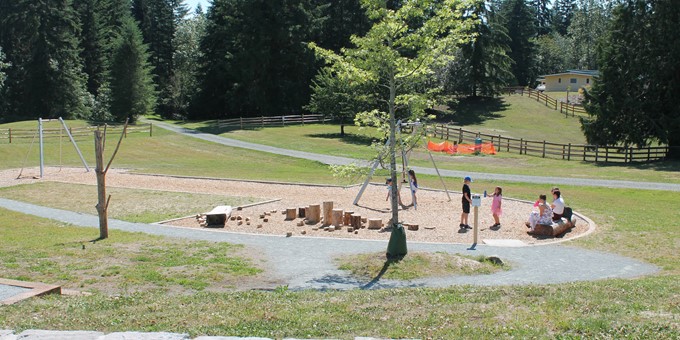 kids play on the zipline at big rock park north's playground in a large grassy area